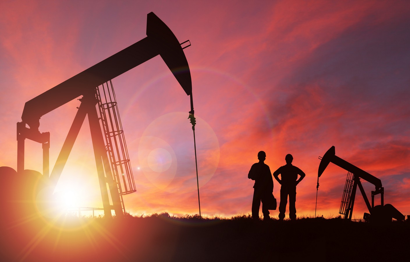 Oilfield truck passing idle pumpjacks at sunset, representing wasted overhead